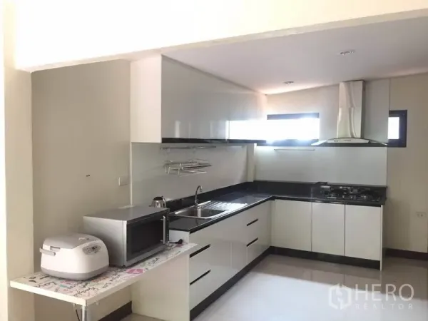Detached House for rent - Modern L-shaped kitchen with white cabinets, black countertops and range hood.