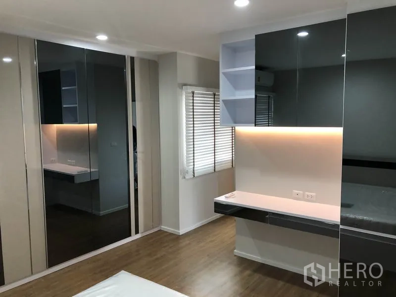 Detached House for rent in Prawet, Bangkok - Bedroom with built-in desk, shelving and mirrored wardrobes with accent lighting.