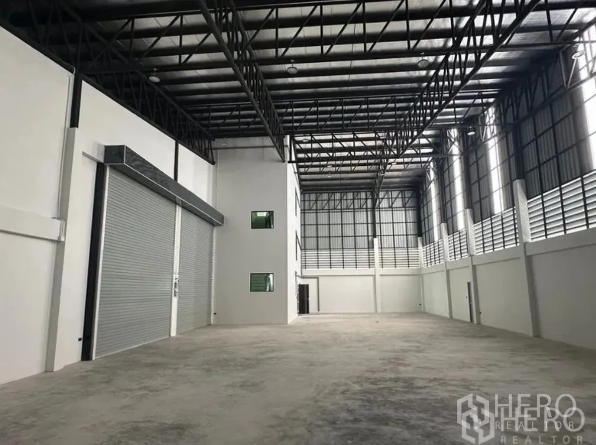 仓库 for sale in Lam Luk Ka, Pathum Thani - 开阔仓储区，设高窗与百叶通风口及双灰色卷闸门。