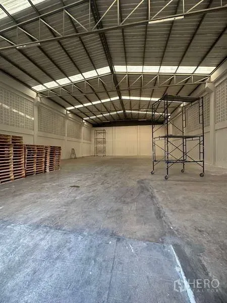 Warehouse for rent in Suan Luang, Bangkok - Open industrial storage area showing steel roof structure and mobile scaffolding.