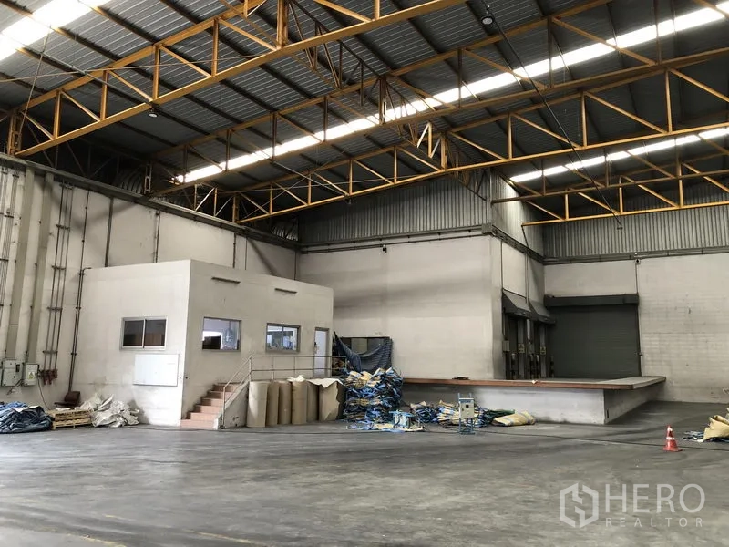 Warehouse for rent in Phra Nakhon Si Ayutthaya - Spacious warehouse interior with high steel trusses and an internal office box.