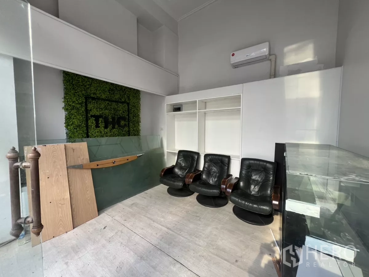 Retail Space for rent - Retail showroom area with green feature wall, built-in shelving, glass counter, and front glass doors.