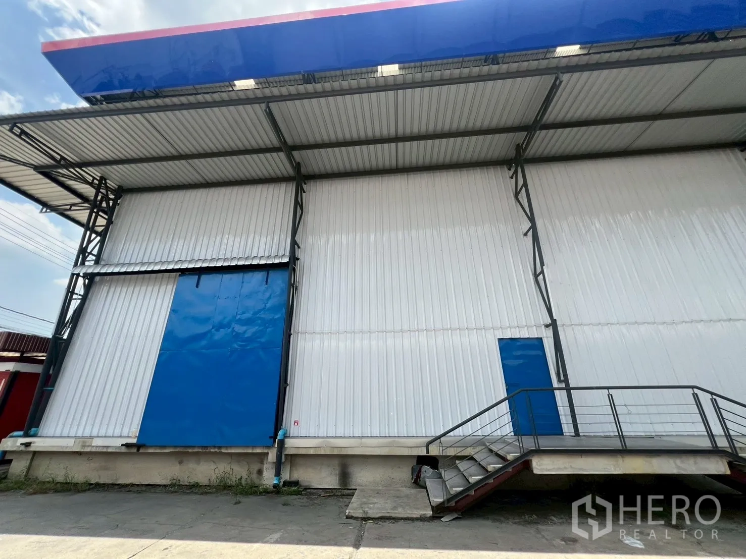 货栈 出租在Lat Krabang, Bangkok - 码头高度装卸平台，蓝色卷门与侧边人行门，置于宽大雨棚下。