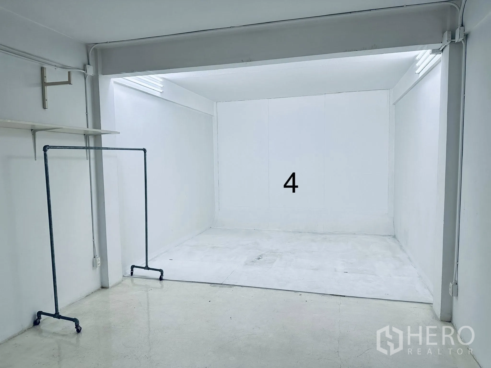 ตึกแถว for rent in Watthana, Bangkok - มุมสตูดิโอผนังขาว ไฟเพดาน และราวแขวนเสื้อผ้าเคลื่อนที่