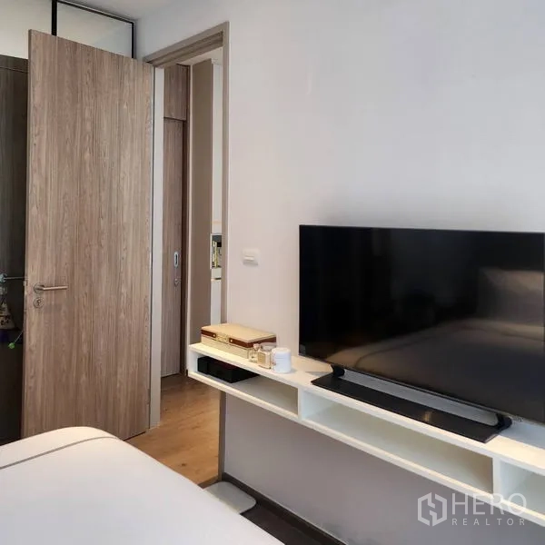 Condominium for rent - Bedroom corner with TV on floating shelf, wood flooring and open door to corridor.