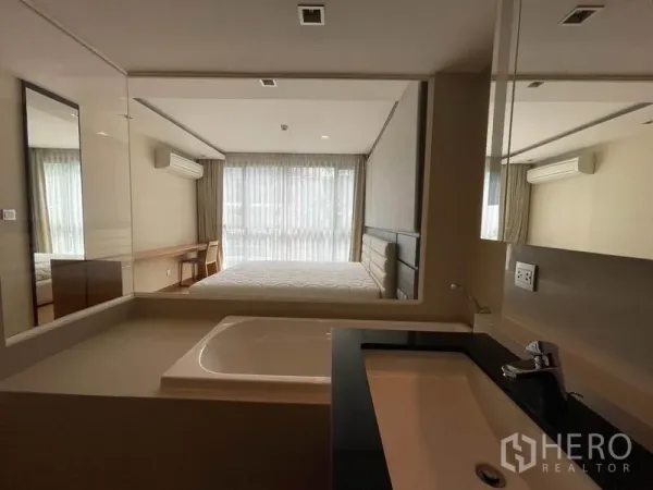 公寓 出售在Watthana, Bangkok - 浴室洗手台，通过玻璃可见明亮卧室。