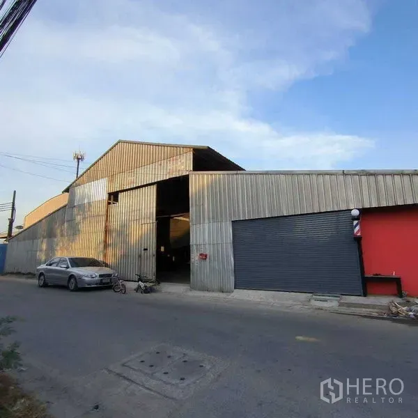 Warehouse for rent in Saphan Sung, Bangkok - Corrugated metal warehouse exterior with wide roller shutter and direct street access.