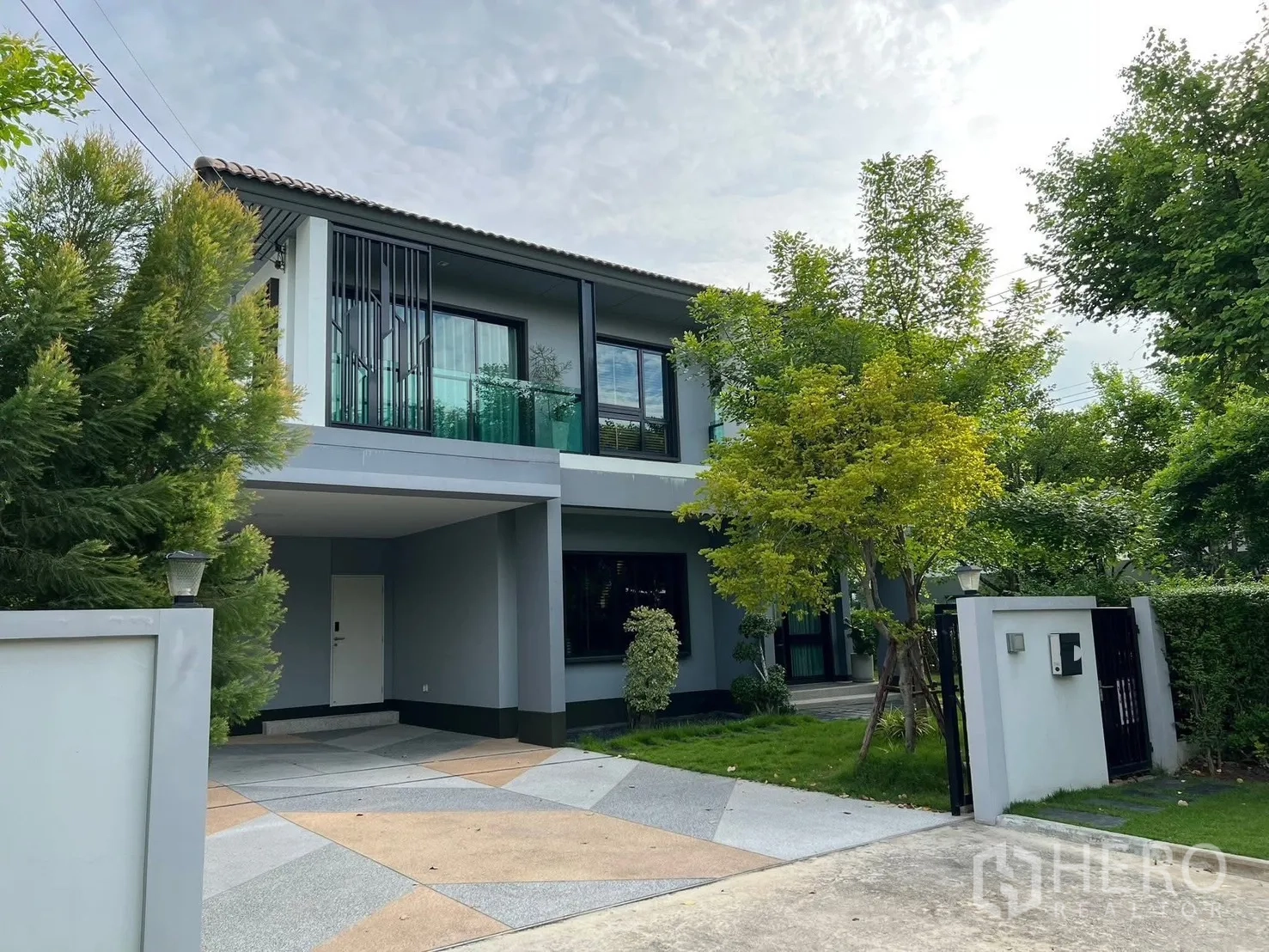 独立式住宅 出租在Bang Phli, Samut Prakan - 住宅正面，车道与有顶车棚，绿树成荫的庭院与大门。