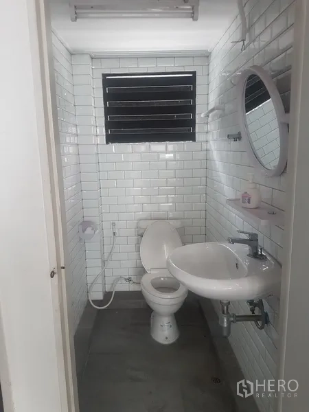 Home Office for sale in Khlong Toei, Bangkok - Compact restroom with white subway tiles, sink and toilet.