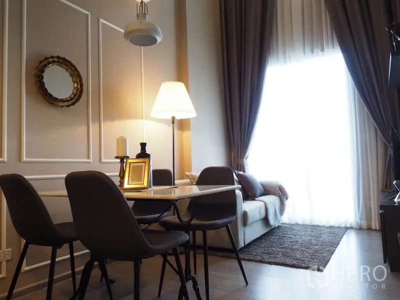Condominium for rent in Khlong San, Bangkok - Dining nook for four with pendant light beside a sofa and large window.