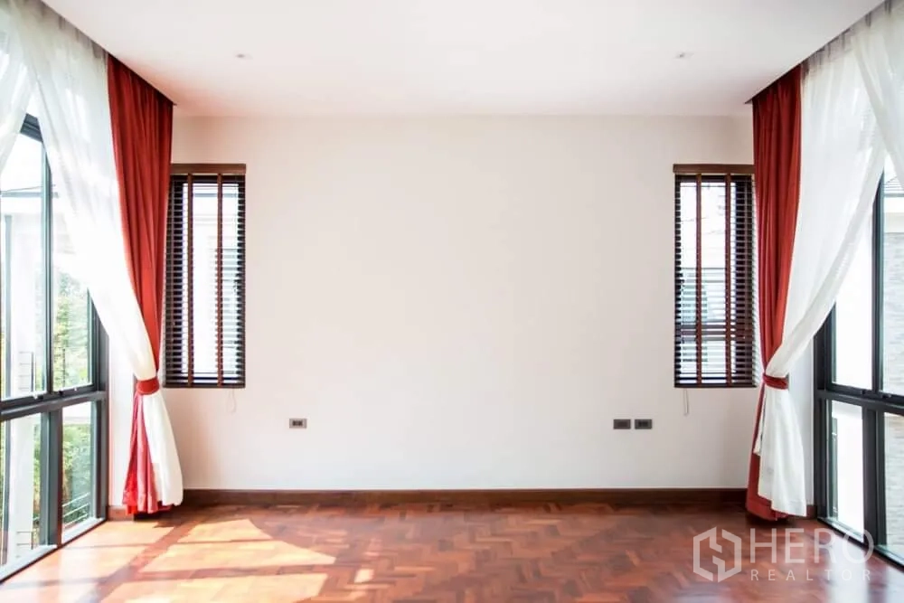 Detached House for rent in Khlong Toei, Bangkok - Bedroom with floor-to-ceiling windows, red curtains and leafy views.