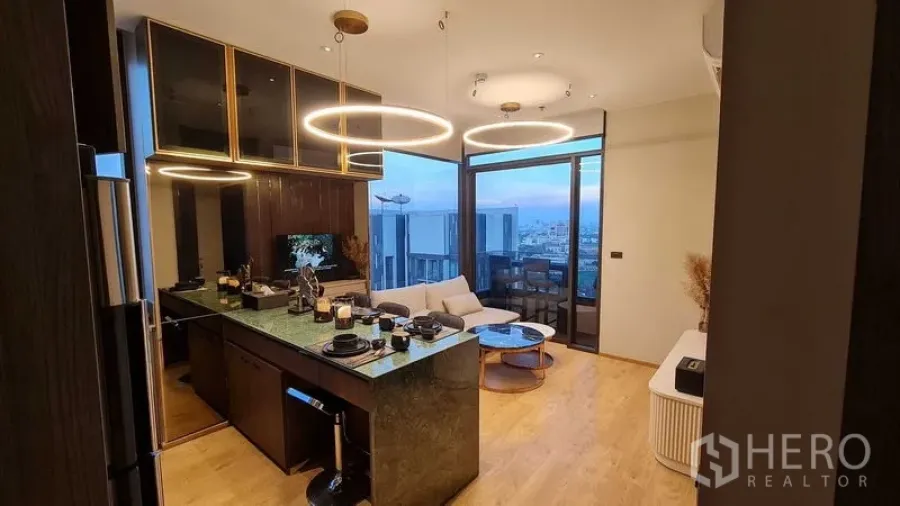 公寓 出租在Watthana, Bangkok - 厨房与起居区，岛台用餐与环形吊灯，享阳台景致。