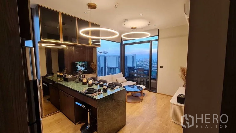 公寓 出租在Watthana, Bangkok - 厨房与起居区，岛台用餐与环形吊灯，享阳台景致。