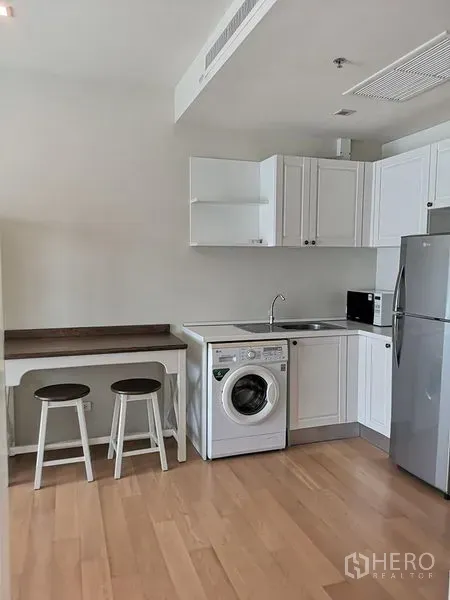 Condominium for rent or sale in Phaya Thai, Bangkok - Compact white kitchen with washing machine, sink, fridge and a breakfast counter.