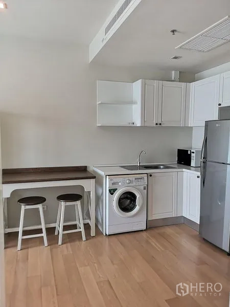 Condominium for rent or sale in Phaya Thai, Bangkok - Compact white kitchen with washing machine, sink, fridge and a breakfast counter.