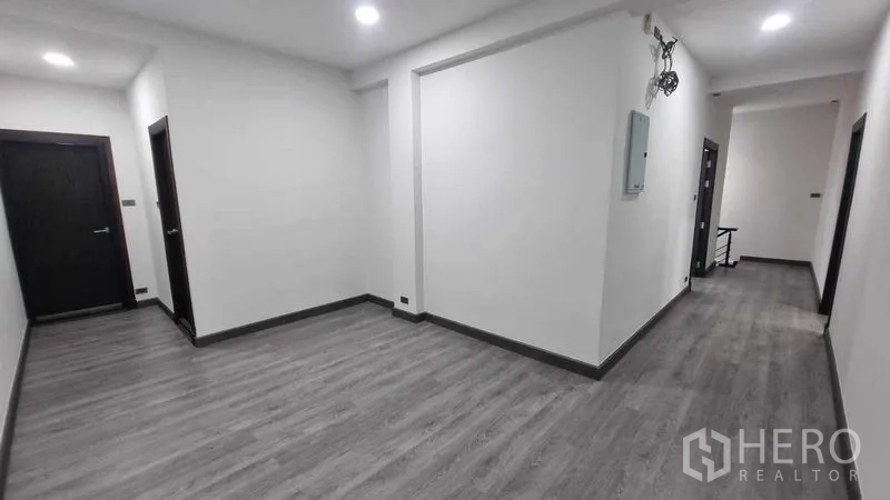 联排别墅 出租在Khlong Toei, Bangkok - 明亮走廊，灰色木纹地板与嵌灯，空间通透。