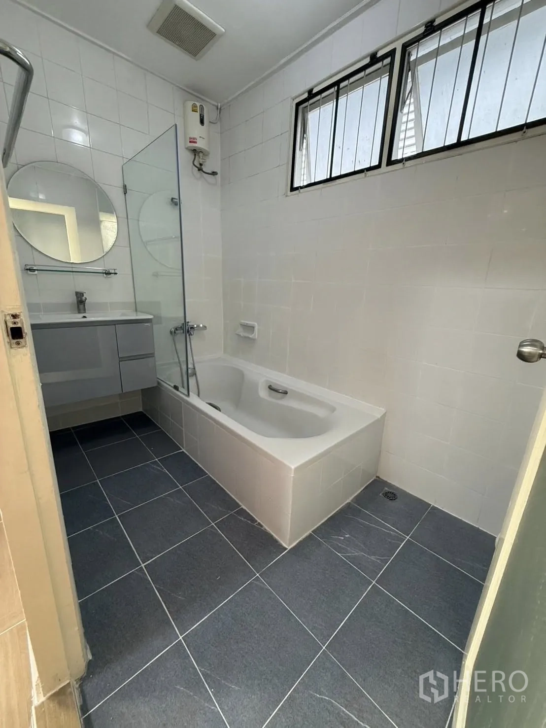 独栋房屋 for rent in Khlong Toei, Bangkok - 浴室配有浴缸、洗手台、壁挂式热水器与窗户。