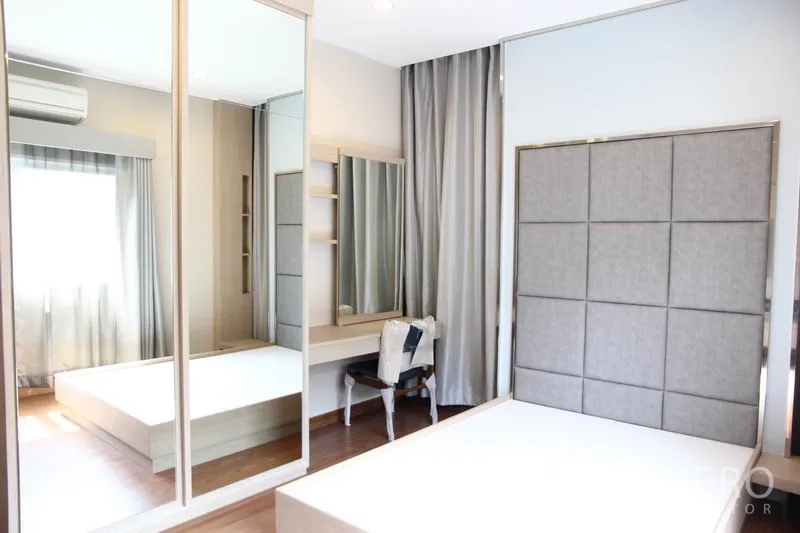 บ้าน ให้เช่าในBang Na, Bangkok - ห้องนอนใหญ่มีหัวเตียงบุผ้า ตู้เสื้อผ้าบานกระจก โต๊ะเครื่องแป้ง และพื้นไม้