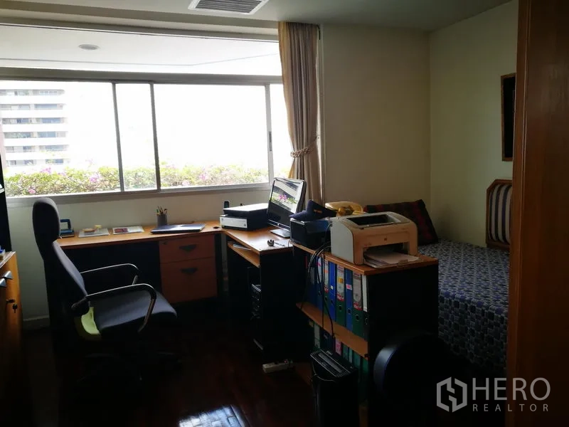 Condominium for rent or sale in Watthana, Bangkok - Home office with long desk, storage and a single daybed by a wide window.