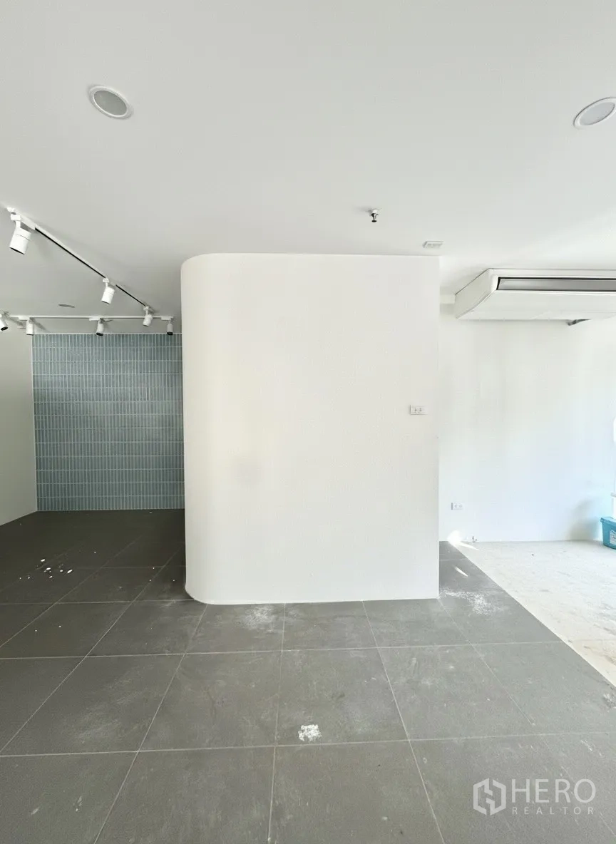 Retail Space for rent - Curved feature wall with grey tiles and a blue tile accent backdrop under track lights.