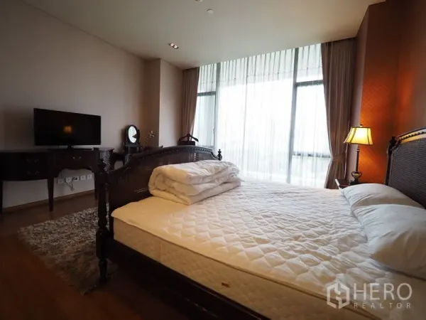 Condominium for rent in Sathon, Bangkok - Master bedroom with king bed, classic wood furniture and sheer curtains.