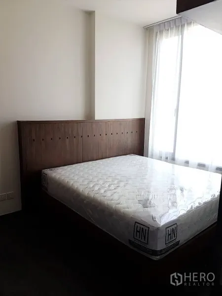 公寓 出租或出售在Watthana, Bangkok - 温馨卧室，木质床头板和大窗户引入自然光。