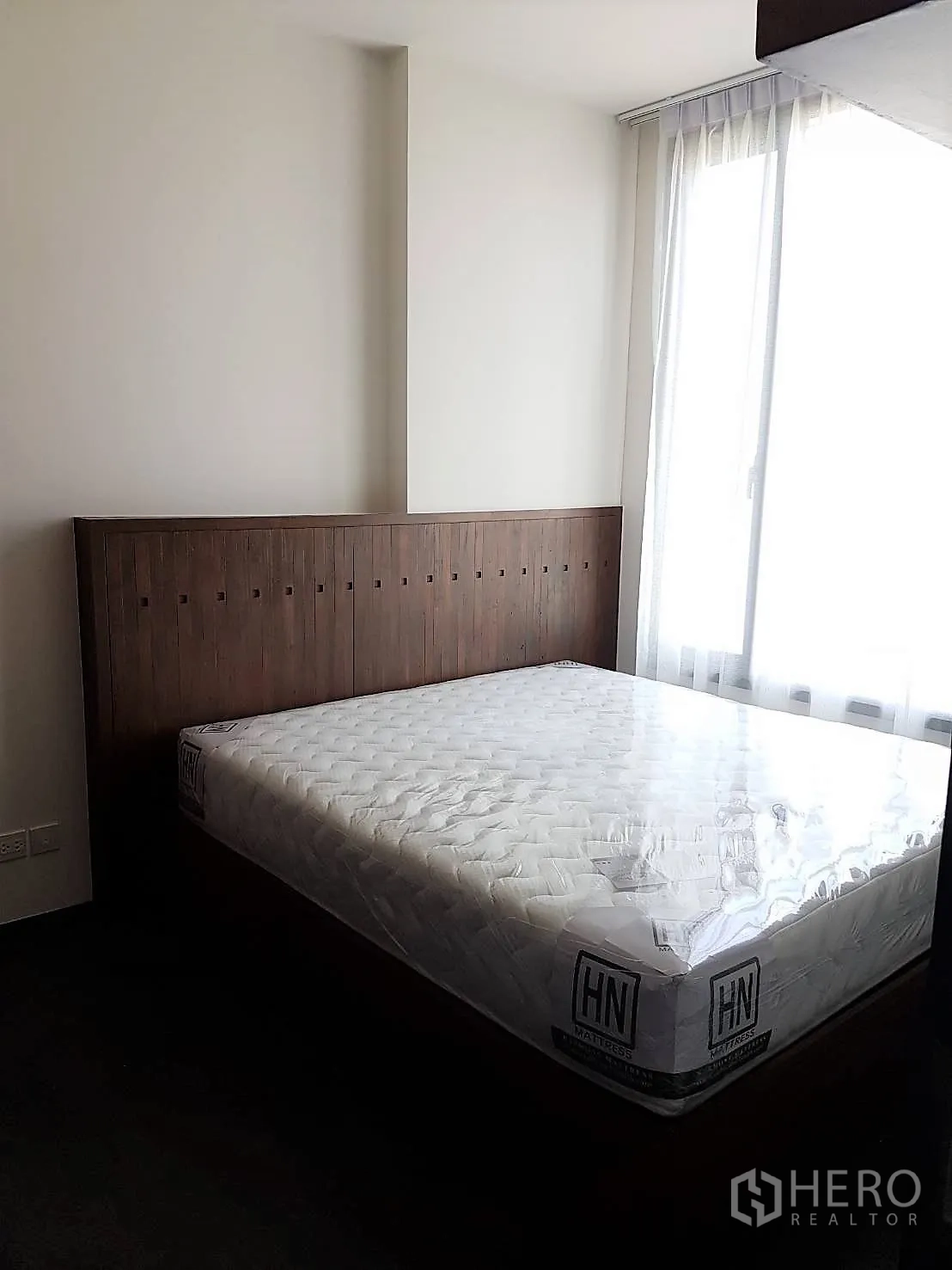 公寓 出租或出售在Watthana, Bangkok - 温馨卧室，木质床头板和大窗户引入自然光。