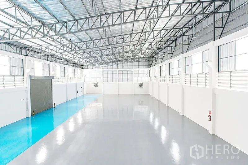 Warehouse for rent in Bang Bo, Samut Prakan - Clear-span warehouse view with blue loading lane and ventilation louvers along the walls.