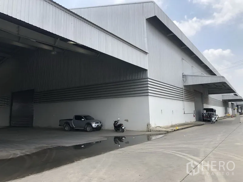 Factory for rent in Wang Noi, Phra Nakhon Si Ayutthaya - Large metal-clad warehouse exterior with a wide covered loading bay, roller shutter door and concrete driveway.