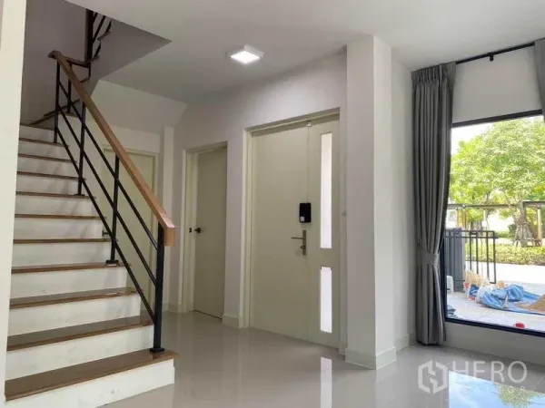 独立式住宅 出租在Khan Na Yao, Bangkok - 明亮玄关，楼梯、电子门锁与面向花园的大窗。