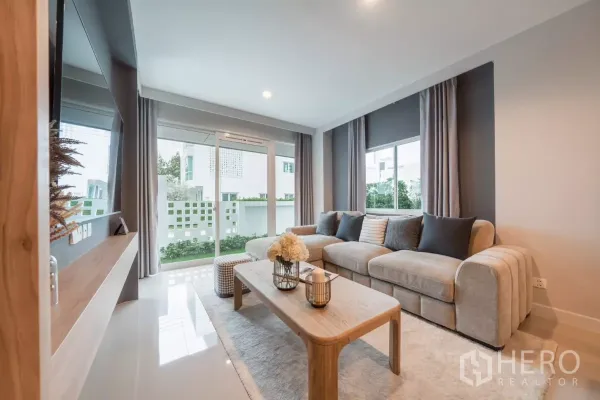Detached House for rent in Saphan Sung, Bangkok - Bright living room with L‑shaped sofa and sliding glass doors to a small garden patio.