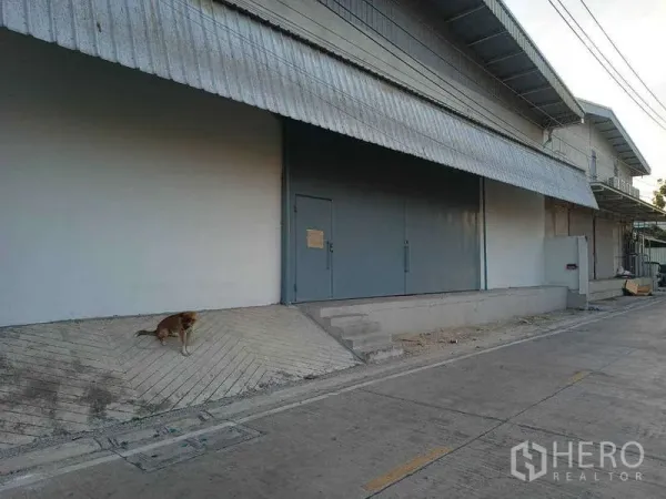 Warehouse for rent in Bang Phli, Samut Prakan - Warehouse exterior with covered loading bay, large steel sliding door and wide access road in Bang Phli.