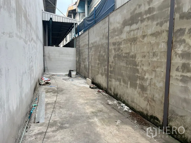 货栈 出租在Bang Sao Thong, Samut Prakan - 两侧围墙之间的混凝土侧院与服务通道。