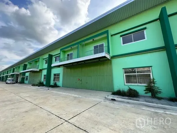 คลังสินค้า ให้เช่าในPathum Thani - ภาพอีกมุมของโกดังสีเขียวพร้อมลานถอยรถกว้างและกันสาด