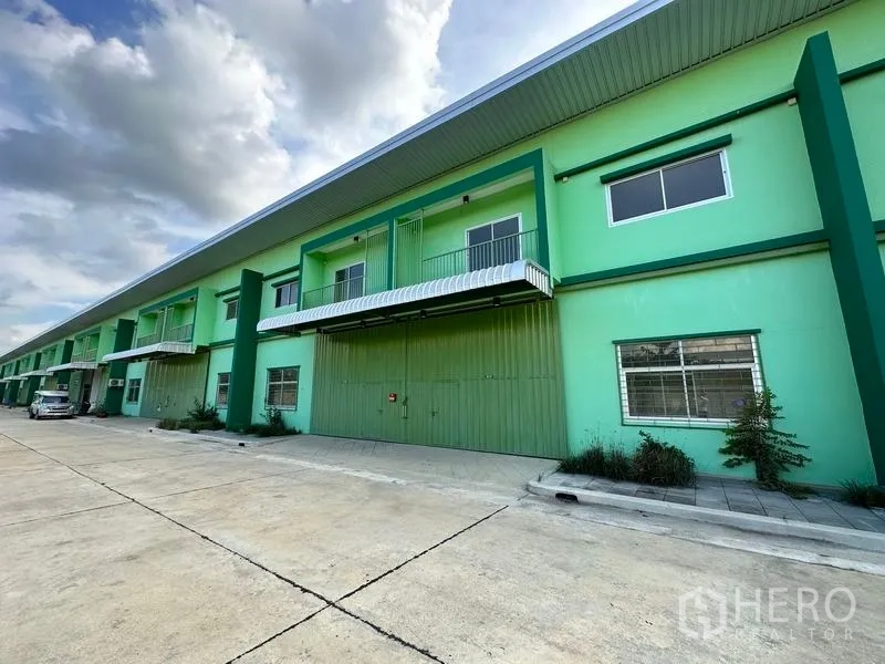 货栈 出租在Pathum Thani - 绿色仓库外观另一角度，宽车道与雨棚一览。