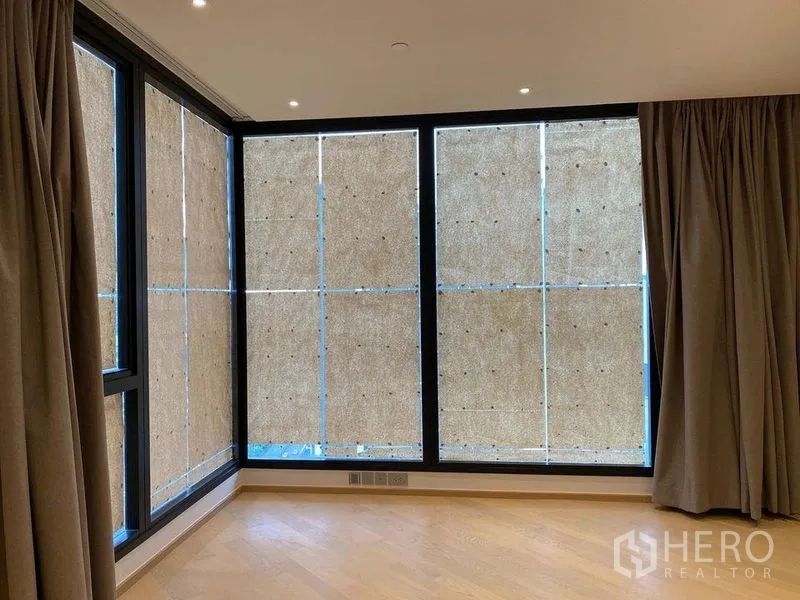 公寓 出售在Din Daeng, Bangkok - 宽敞房间，落地窗与窗帘，浅色木地板。