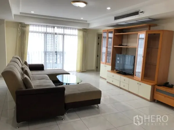 Condominium for rent in Watthana, Bangkok - Bright living room with L-shaped sofa, TV cabinet and sliding doors to the balcony.