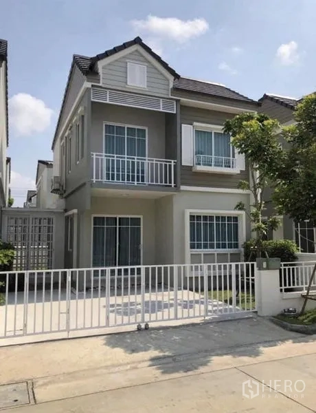 带办公室的家 出租在Samut Prakan - 两层现代住宅外观，带阳台、带门庭院车位与小草坪，街区宁静。