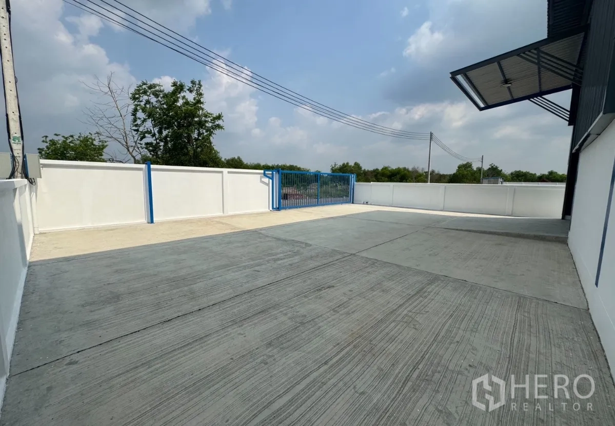 Warehouse for rent in Khlong Luang, Pathum Thani - Wide concrete loading yard inside the compound with sliding gate.