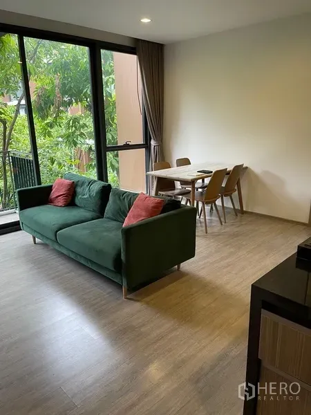 Condominium for rent in Watthana, Bangkok - Open-plan living and dining area with floor-to-ceiling windows and garden view balcony.