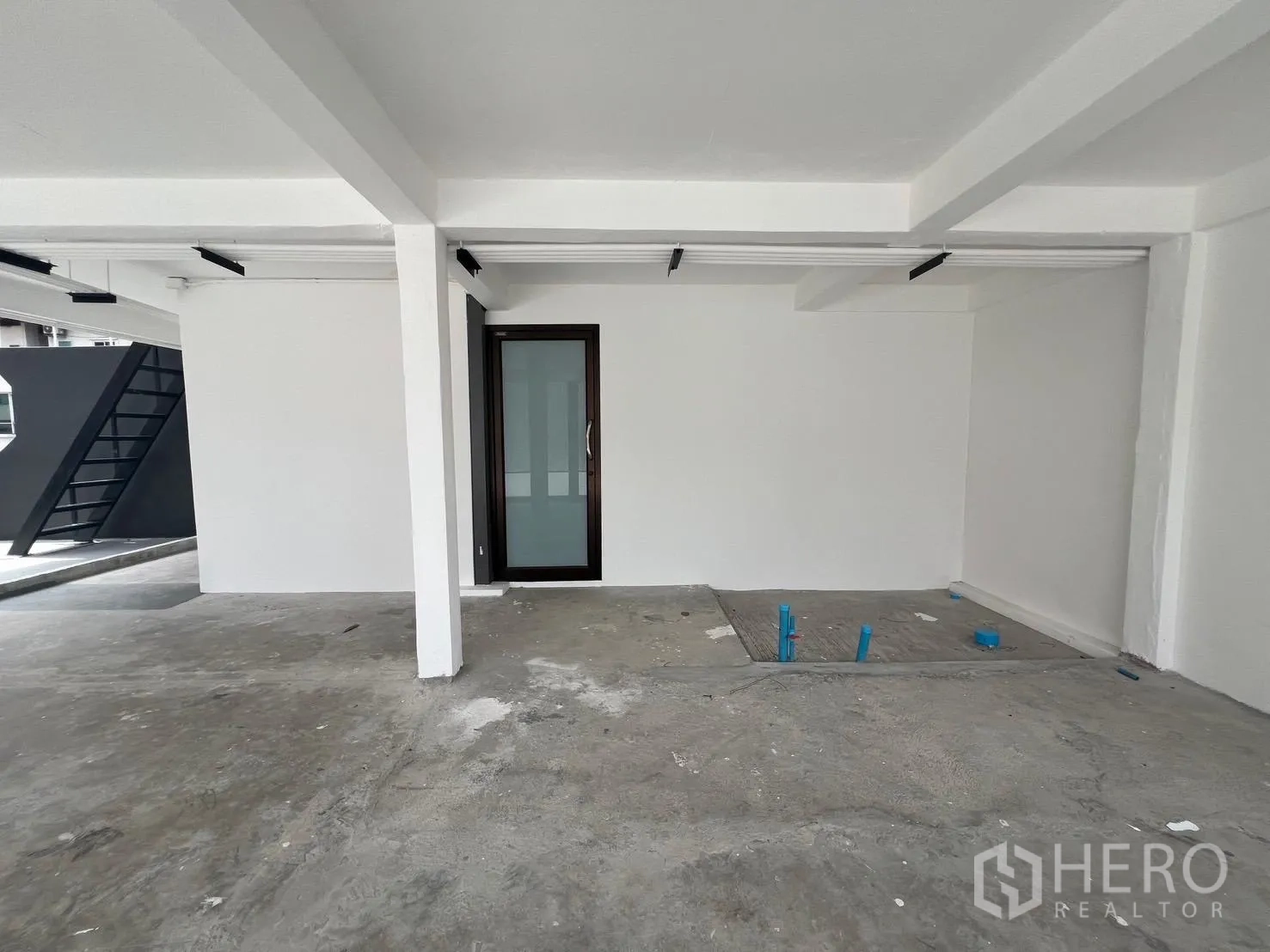 Retail Space for rent in Bang Rak, Bangkok - Unfinished interior with frosted glass door, track lighting, and visible plumbing outlets on concrete flooring.