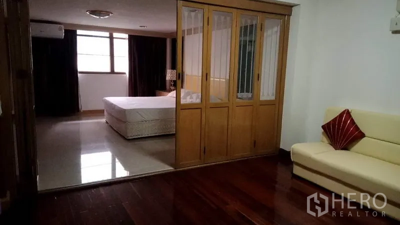 联排别墅 出租在Khlong Toei, Bangkok - 大套间，玻璃分隔衣柜、米色沙发与亮面木地板。