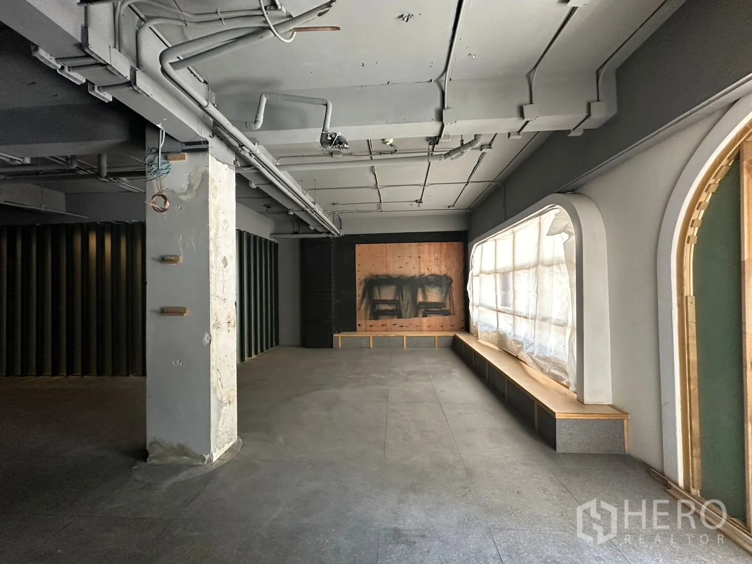 พื้นที่ขายของ for rent in Watthana, Bangkok - พื้นที่ภายในร้านแบบเปิดโล่ง เพดานโชว์ท่อ เสาคอนกรีต และม้านั่งใต้หน้าต่างโค้ง.