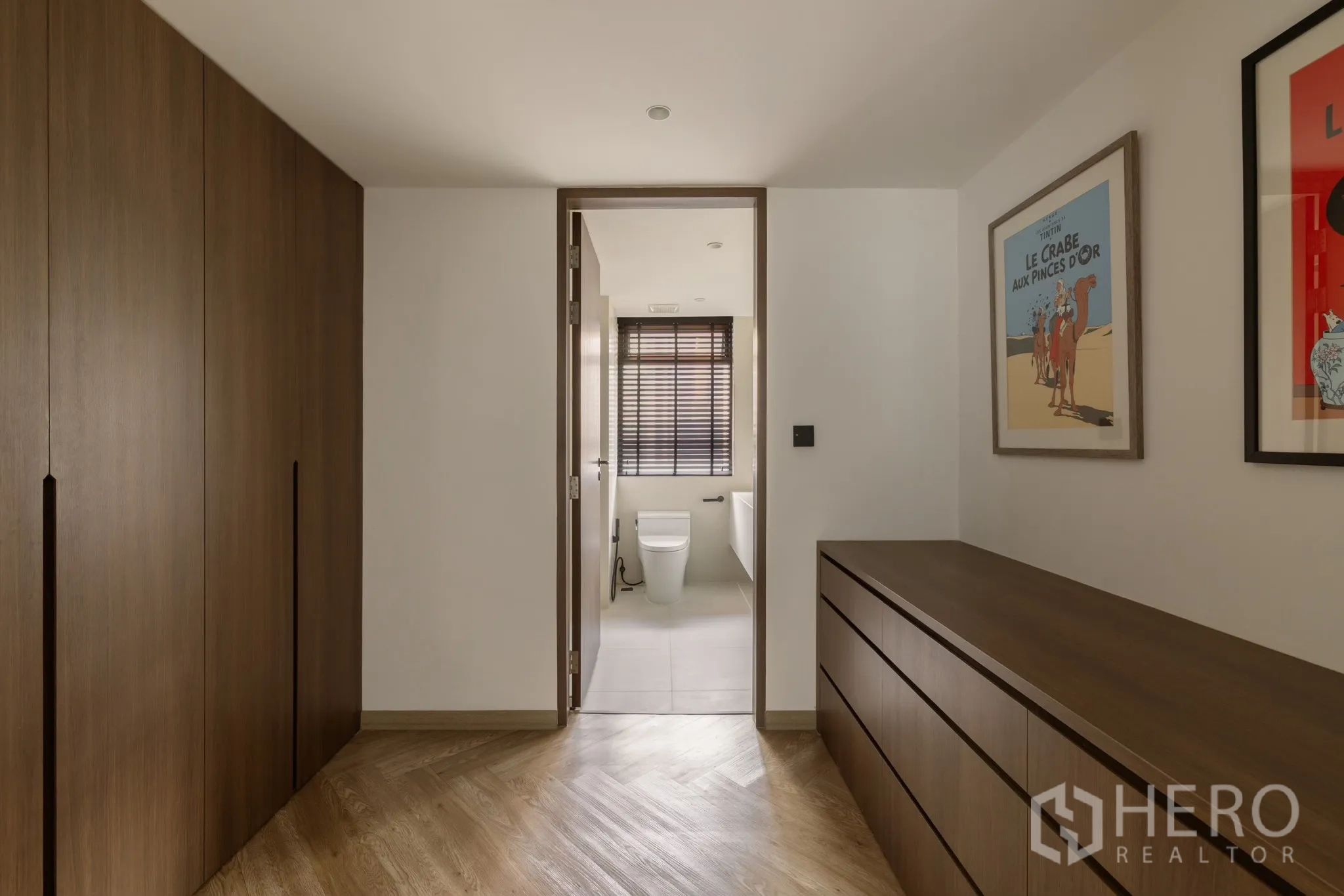 Condominium for sale in Khlong Toei, Bangkok - Dressing corridor with built‑in wardrobes and drawers leading to a bathroom with window blinds.