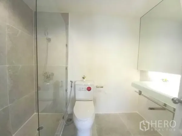公寓 出租在Khlong Toei, Bangkok - 浴室采用玻璃淋浴间、马桶与宽镜面台盆，浅色瓷砖。