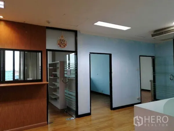 办公空间 出租在Bueng Kum, Bangkok - 木质接待台，旁为玻璃隔间与书架。