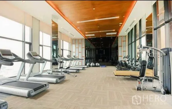Condominium for rent in Bang Rak, Bangkok - Condo fitness center with treadmills, strength machines and large windows.