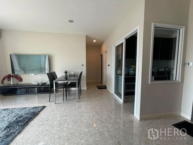 Condominium for sale in Khlong Toei, Bangkok - Dining nook with wall-mounted TV, sliding door to separate kitchen and hallway.