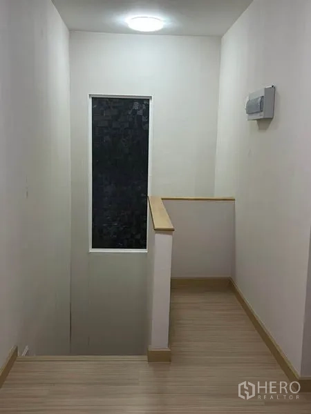 Detached House for sale in Khlong Toei, Bangkok - Stair landing with wood flooring and a tall window for natural light.