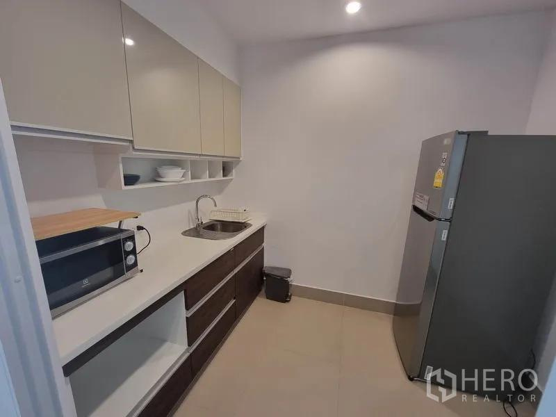 公寓 出租在Ratchathewi, Bangkok - 现代狭长厨房，亮面吊柜、水槽、微波炉与大冰箱